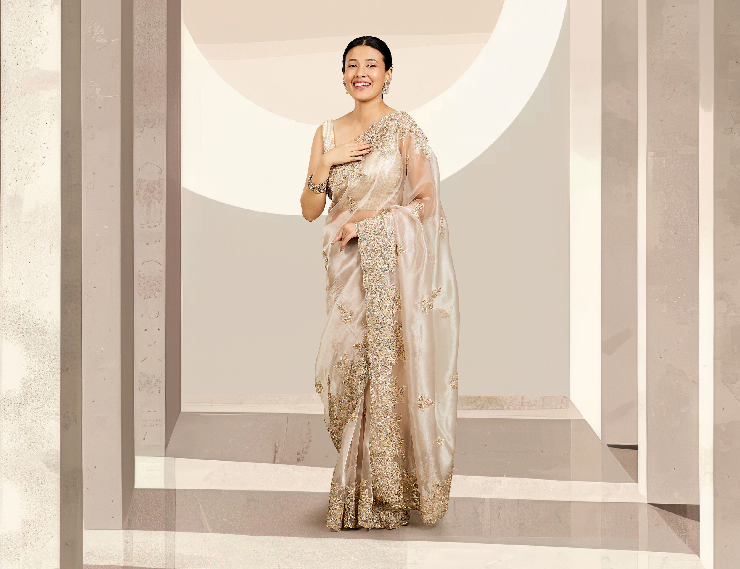 Woman wearing an elegant golden designer saree, styled beautifully for a balanced petite look.